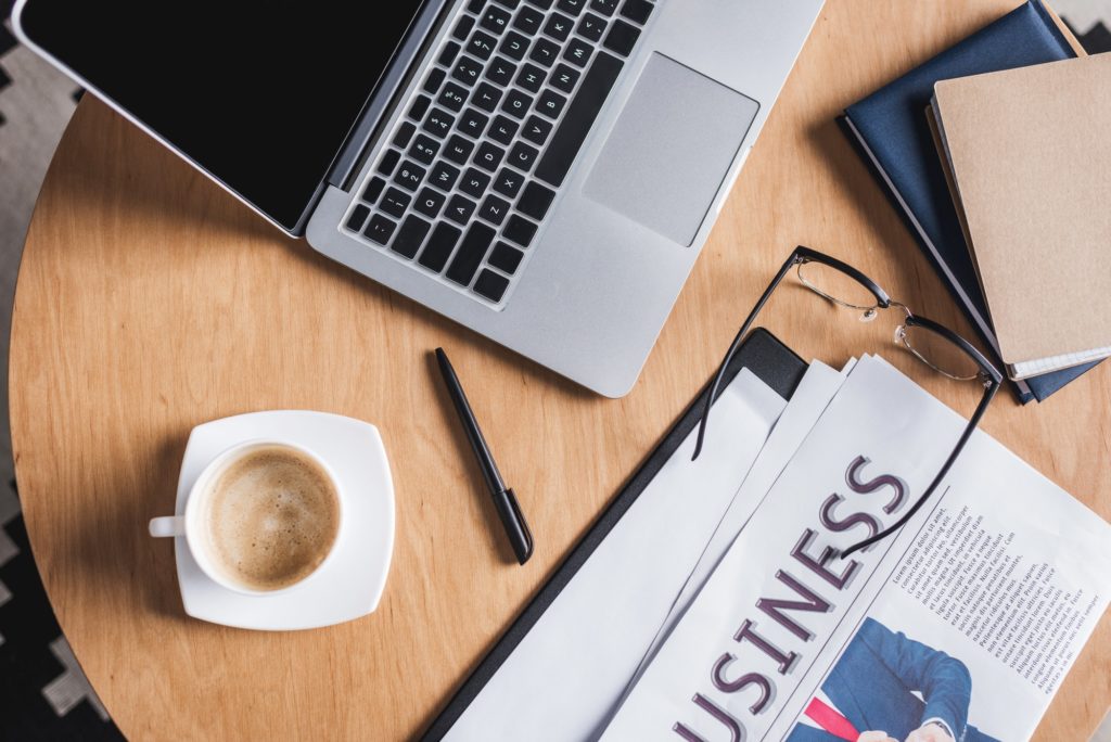 top view of business workplace with laptop and newspaper