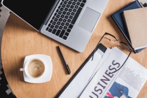 top view of business workplace with laptop and newspaper